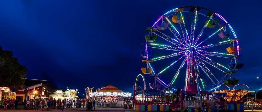 State fair at night with ferris wheel lit up