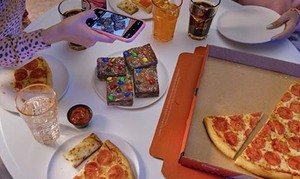 Girl taking a picture of her Casey's pizza, Cheesy Breadsticks, and Party Brookie at a party