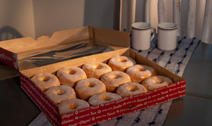 A dozen glazed donuts in a softly lit room
