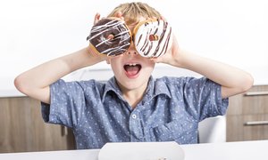 Boy goofily makes a face using two donuts