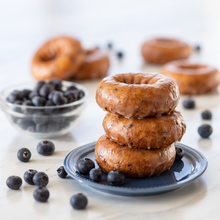 A stack of Casey's Blueberry Cake Donuts with a bowl of blueberries